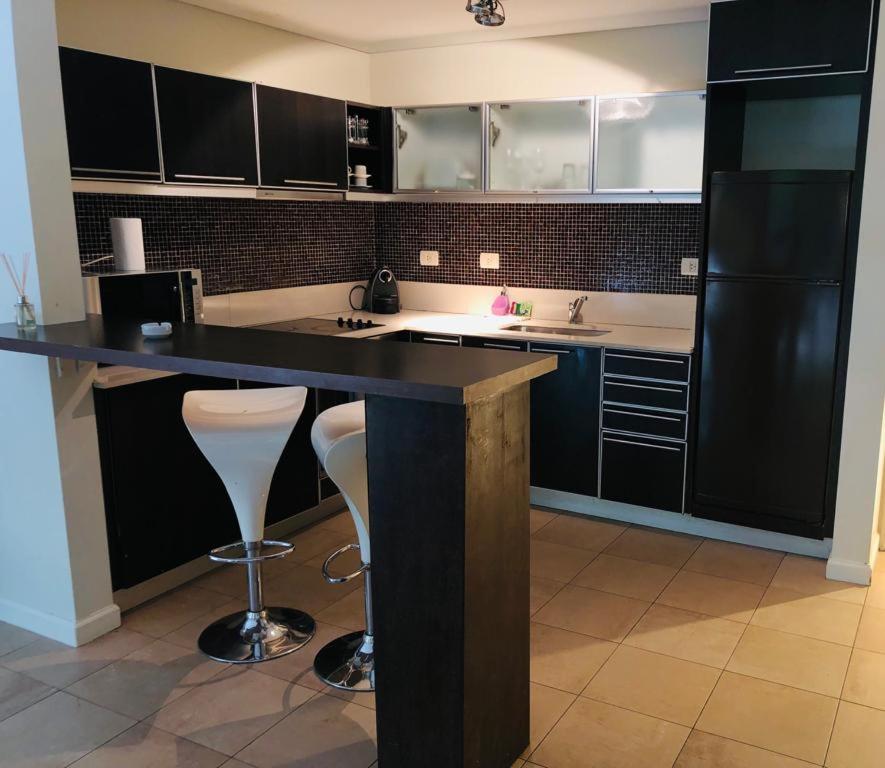 a kitchen with black cabinets and a counter with stools at Alquiler Puerto Madero in Buenos Aires