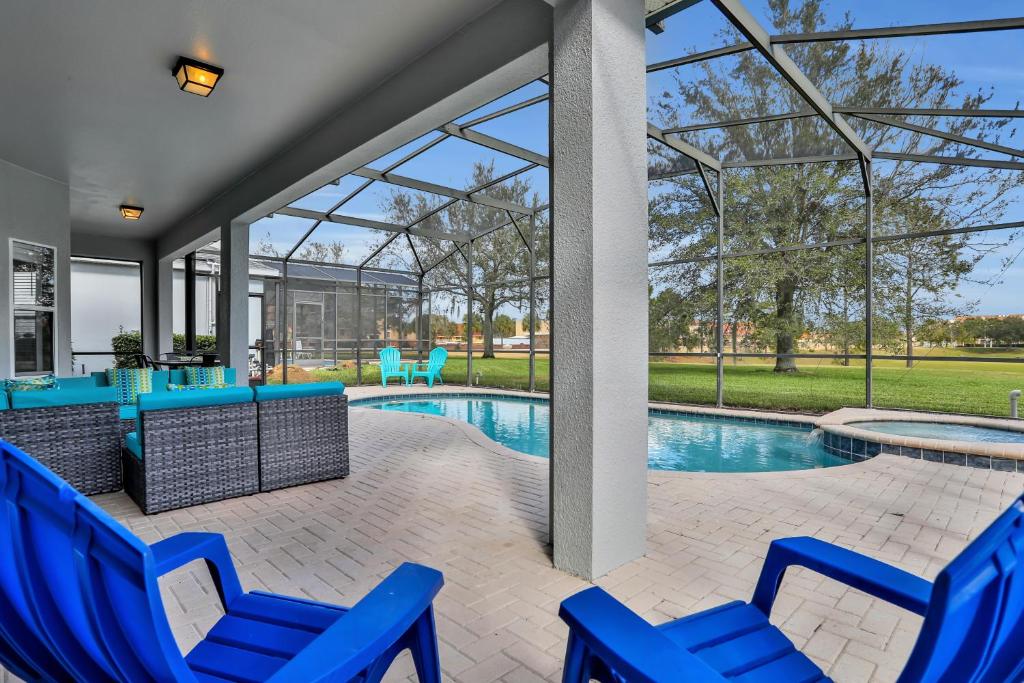 a patio with blue chairs and a swimming pool at Themed Luxury 6BR Getaway with Resort Amenities in Orlando