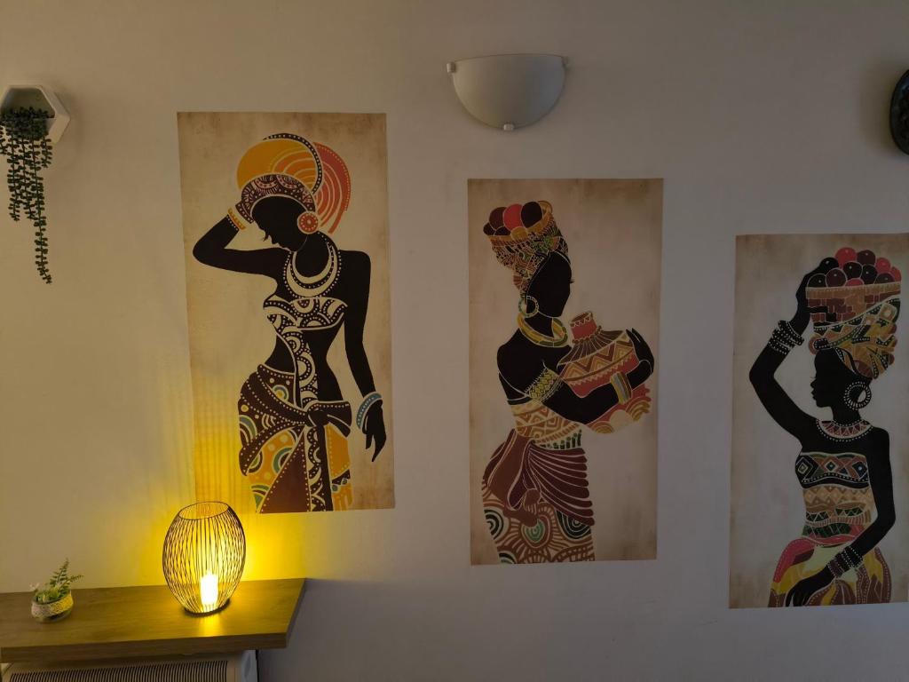 three paintings of women on a wall with a lamp at Por A Mor in Figueiró dos Vinhos