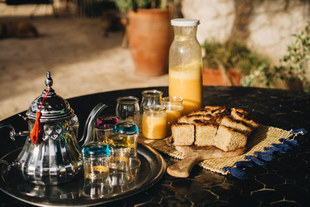 a table with a plate of bread and a bottle of juice at Yogam villa Essaouira in Ghazoua