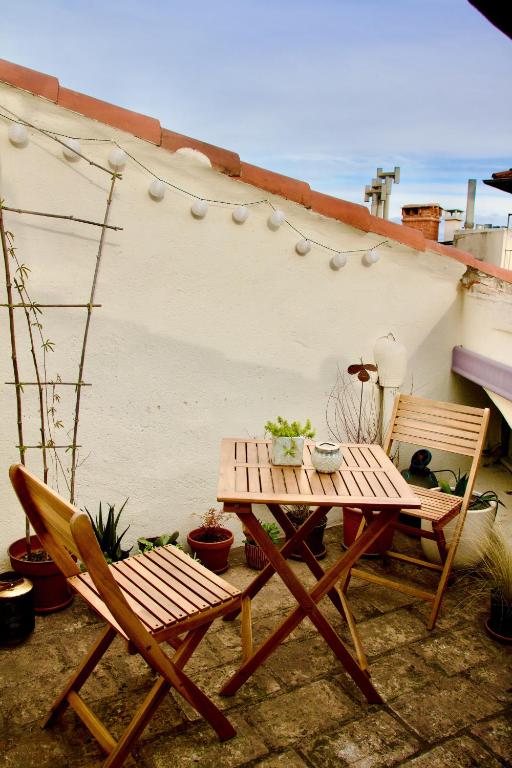 une table en bois et deux chaises à côté d'un bâtiment dans l'établissement Joli studio avec terrasse-jardin sur les toits, coeur historique, à Montpellier