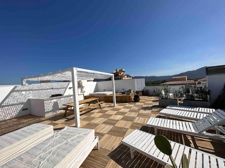 a rooftop deck with white chairs and a view of the ocean at Appartement- rooftop à Rosas in Roses
