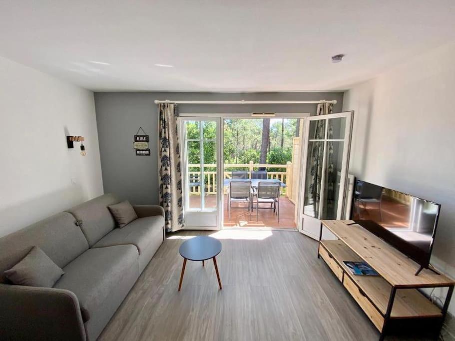 un salon avec un canapé et une télévision à écran plat dans l'établissement Appart moderne grande piscine Lacanau océan pinède, à Lacanau