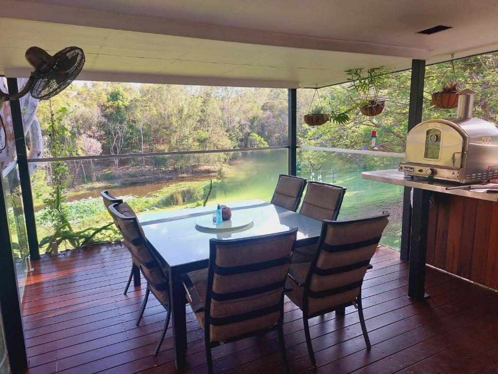 uma sala de jantar com mesa e cadeiras e uma grande janela em kin kin cottage, Noosa hinterland, walk to town. em Kin Kin