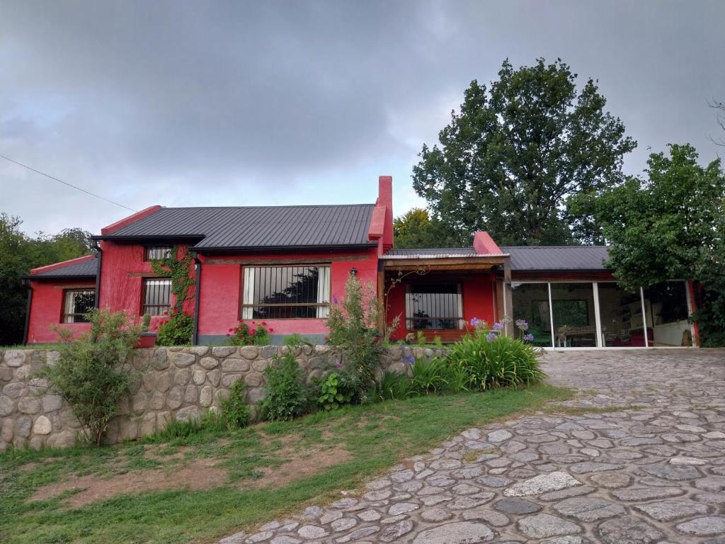 uma casa vermelha com uma entrada de pedra em frente em Casa de campo en tafi del valle em San Miguel de Tucumán
