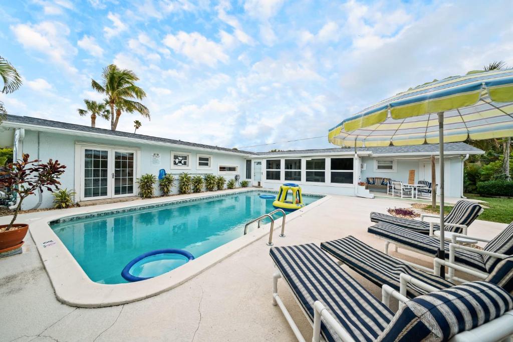 einen Pool mit Stühlen und einem Sonnenschirm in der Unterkunft Skipper's Landing - 4 Bedroom with Heated Pool in Cocoa Beach