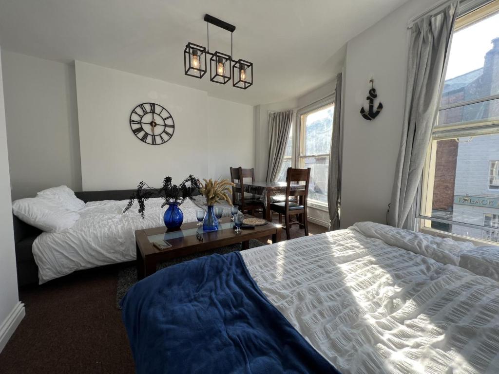 una camera con due letti, un tavolo e un orologio di Blue shell a Scarborough