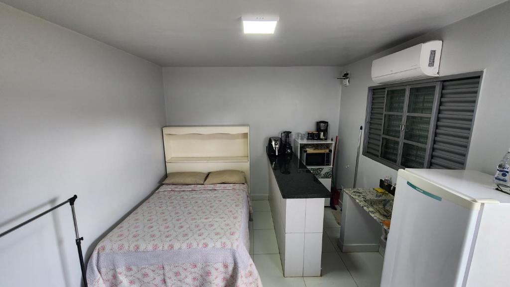 małą sypialnię z łóżkiem i kuchnią w obiekcie Quitinete Ar Condicionado WIFI Garagem Individual w mieście Goiânia