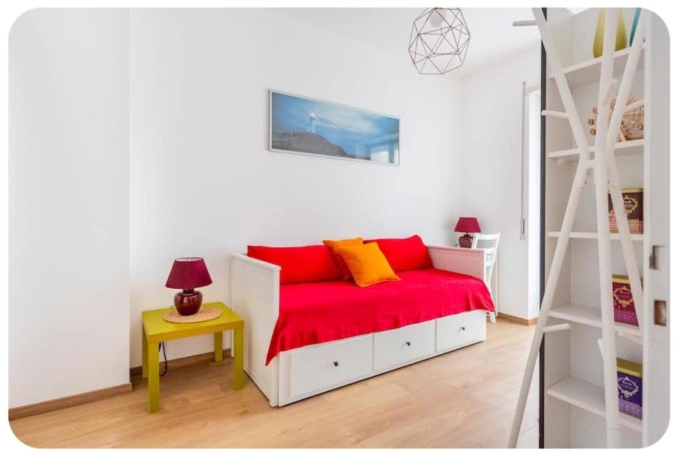 Un dormitorio con una cama con sábanas rojas y una escalera en Casa Rizzoli - bilocale vicinissimo M2, en Milán