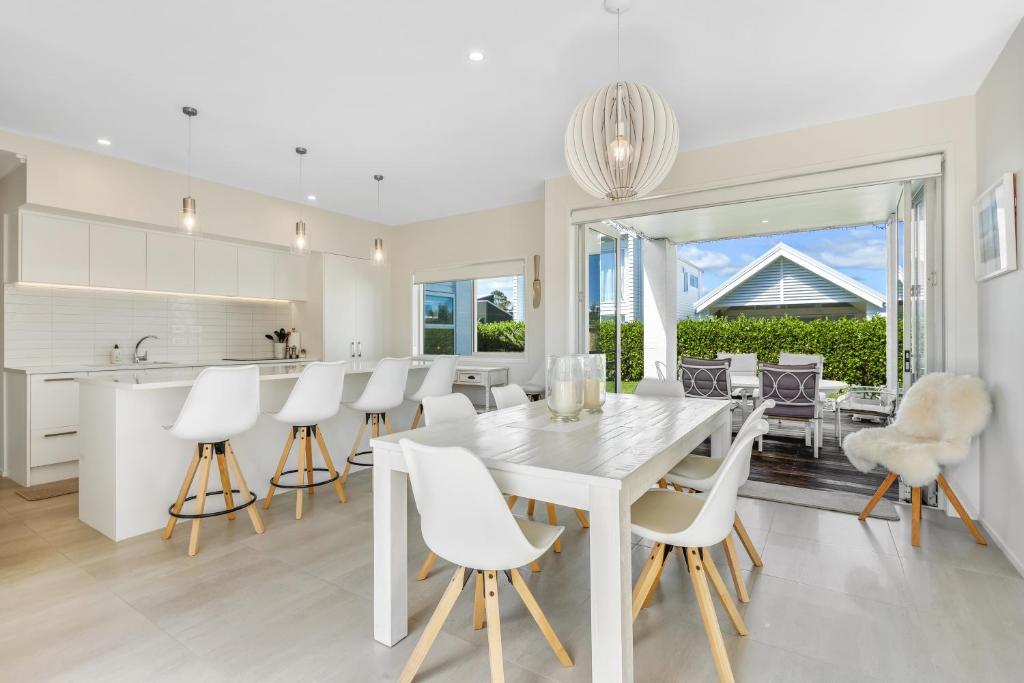 a kitchen and dining room with a white table and chairs at Estuary Bliss Getaway in Mangawhai