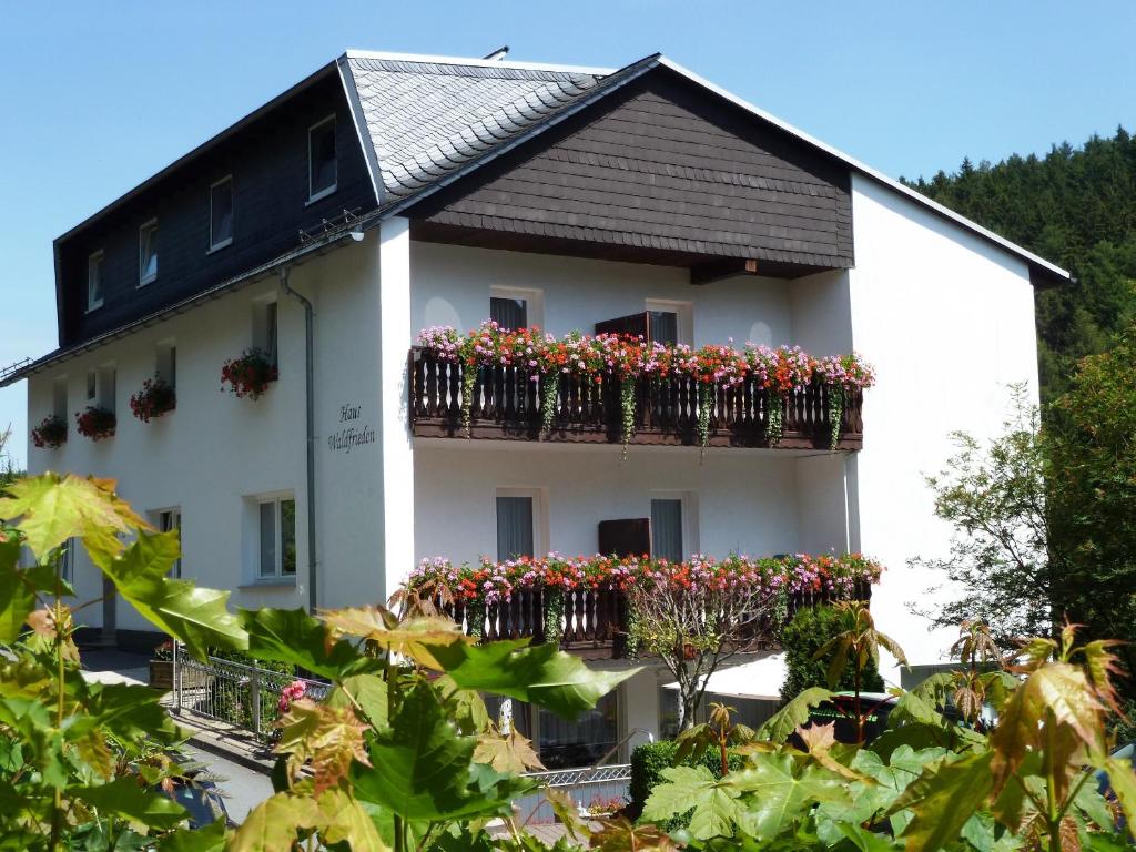 a white building with flowers on the balconies at Pension Haus Waldfrieden, MeineCardPlus inklusive in Willingen