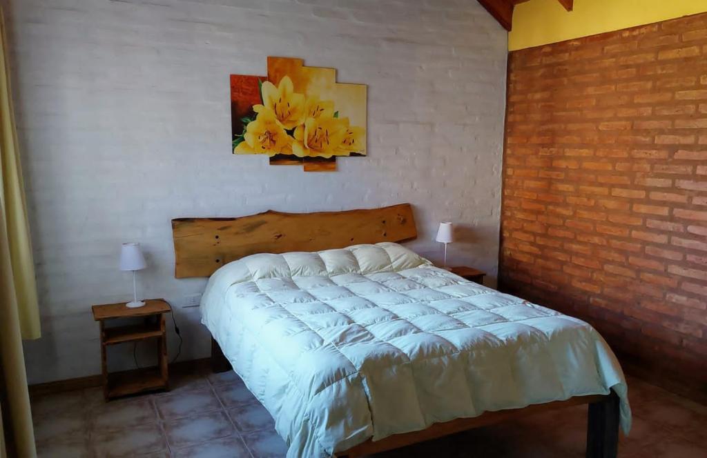 1 dormitorio con 1 cama y una pintura en la pared en Cabañas La Delfina en Potrero de los Funes
