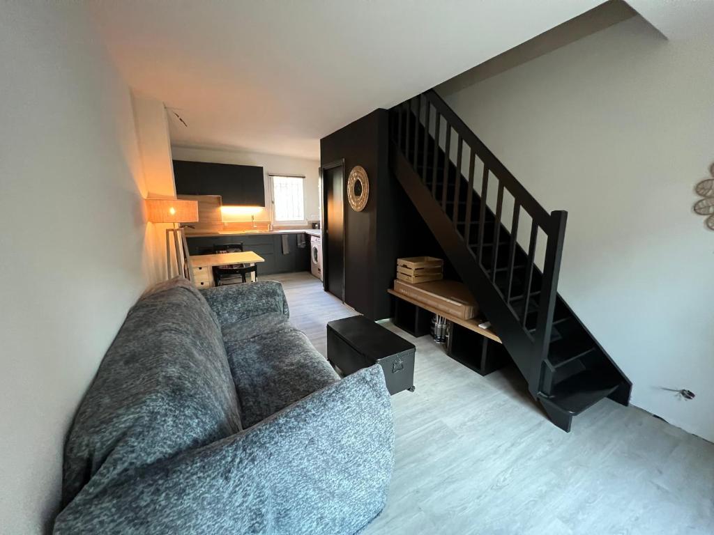 een woonkamer met een bank en een trap bij Maison avec jardin in Le Grau-du-Roi