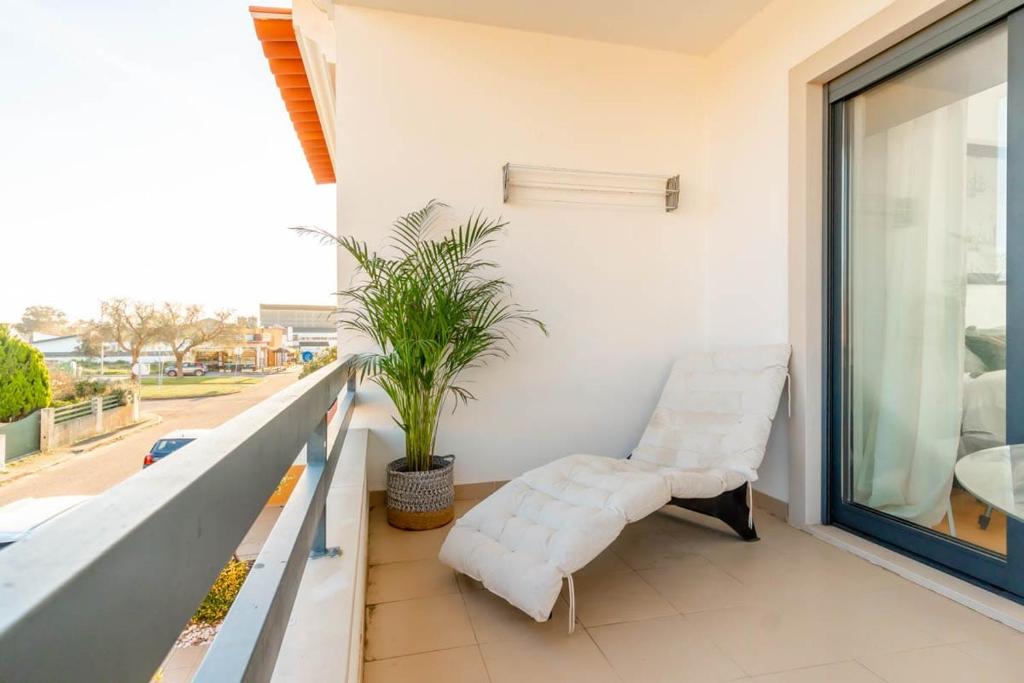 a balcony with two white chairs and a plant at Quarto Brejos-Azeitão in Aldeia Rica