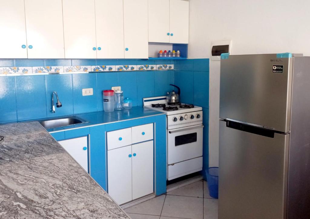 eine blaue Küche mit einem Herd und einem Kühlschrank in der Unterkunft Departamento de verano - CAMANA in Camaná