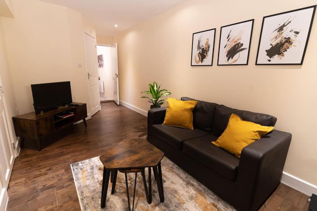 a living room with a black couch and yellow pillows at Charming One-bed Flat in Dagenham