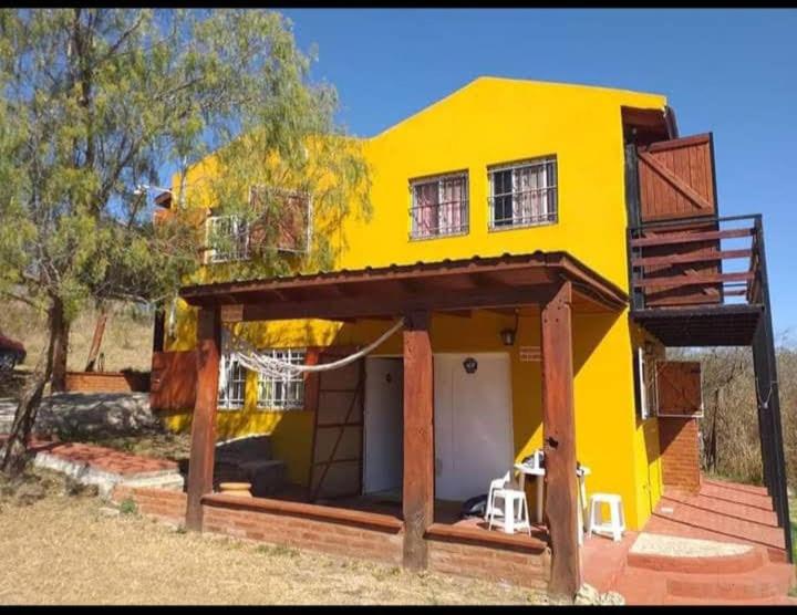 ein gelbes Haus mit einer Veranda und einer Terrasse in der Unterkunft Casa en Balcón de Mallín, Mirador del Lago in Bialet Massé