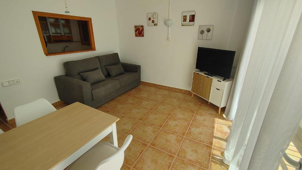 ein Wohnzimmer mit einem Sofa und einem TV in der Unterkunft Formentera Suite 8 in Es Pujols