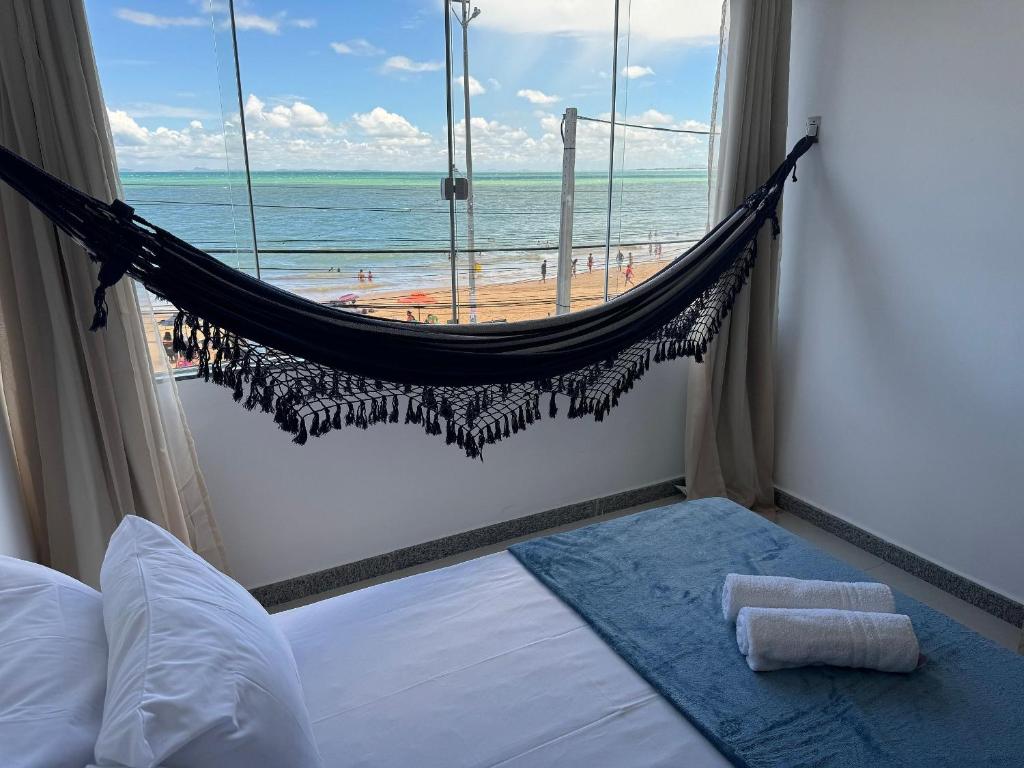 a hammock in a bedroom with a view of the beach at Paraiso Tropical a beira mar - WIFI 200MB - TV Smart - Cozinha equipada - Portaria 24h in Rio das Ostras