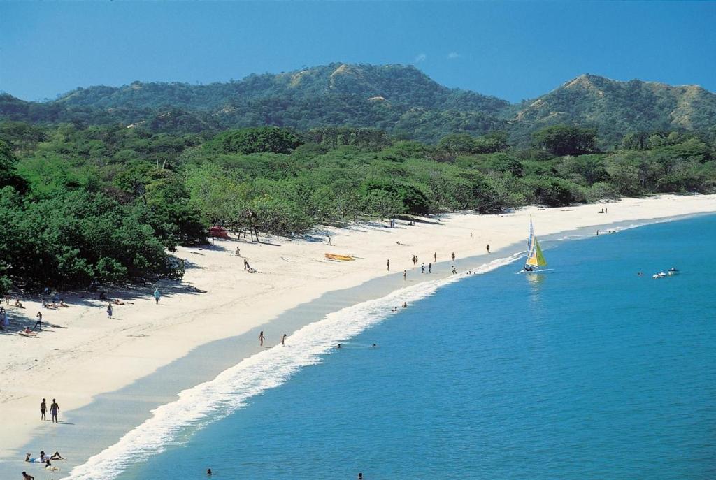 a group of people on a beach with a sailboat at SelvaToSleep in Quepos