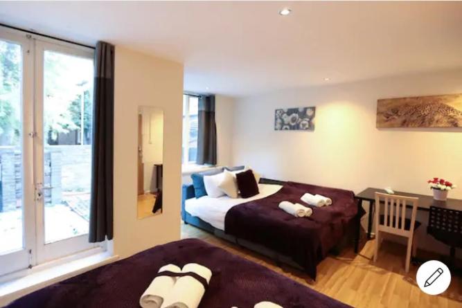 1 dormitorio con 2 camas, escritorio y ventana en Comfy Bedrooms near Euston Station - 1 Exmouth, en Londres