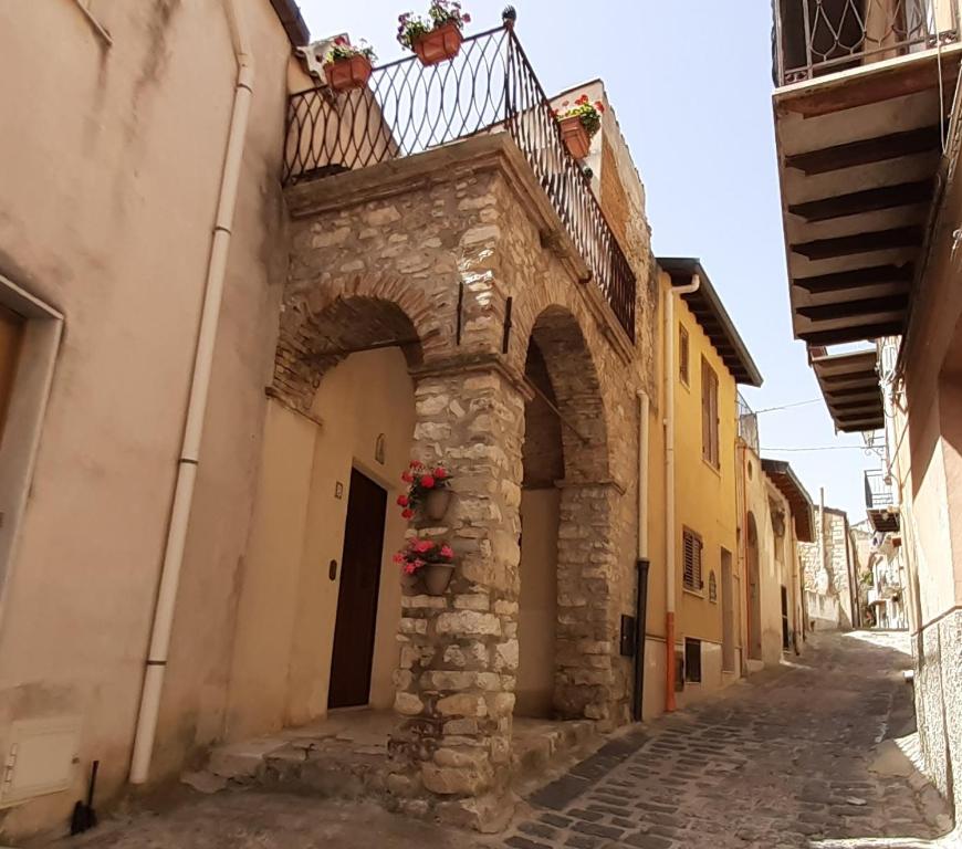 un vicolo con un edificio con balcone e fiori di Archi di San Giacomo a Cammarata