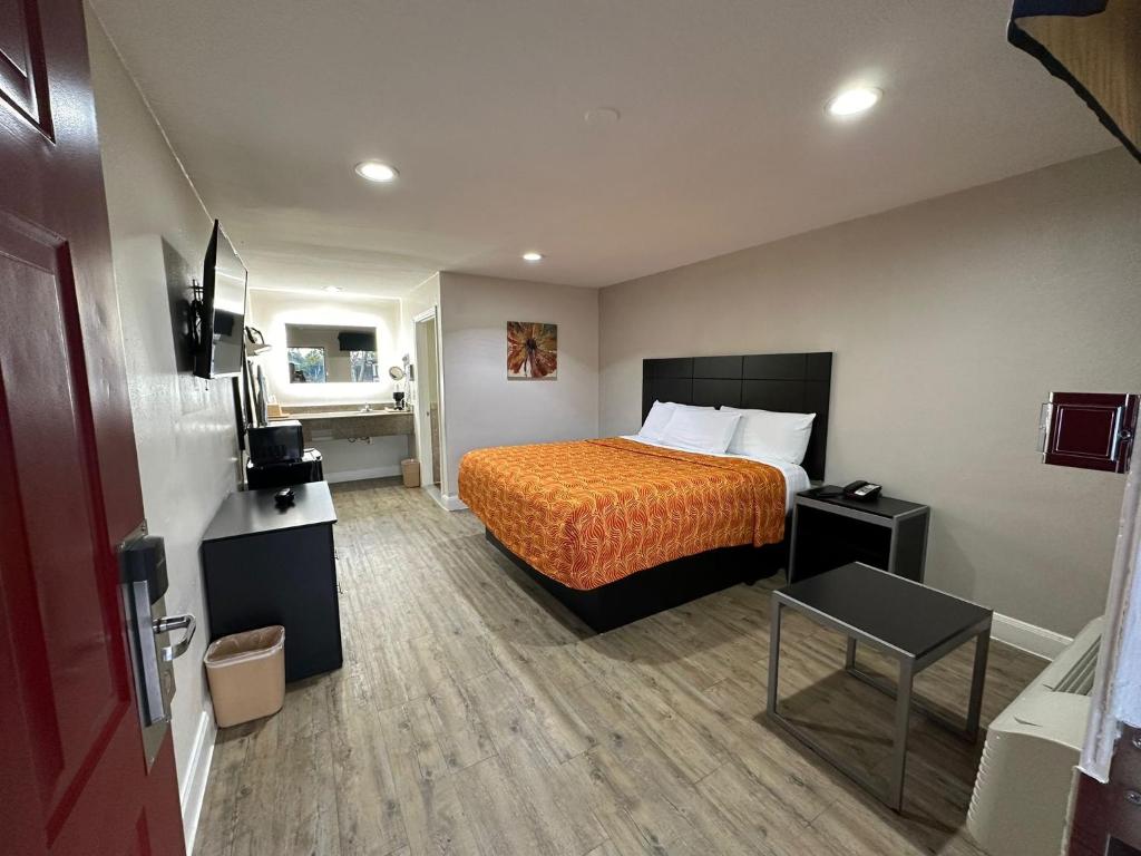 ヒューストンにあるPalace Inn I-45 & Bellfortのオレンジ色のベッドカバーが付いたベッドが備わるホテルルームです。