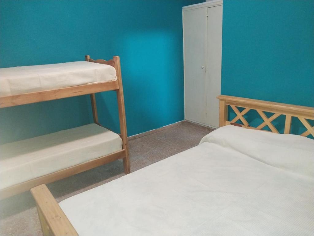 Ce lit se trouve dans un dortoir doté de 2 lits superposés et d'un mur bleu. dans l'établissement La Huella, à Colonia Chapadmalal