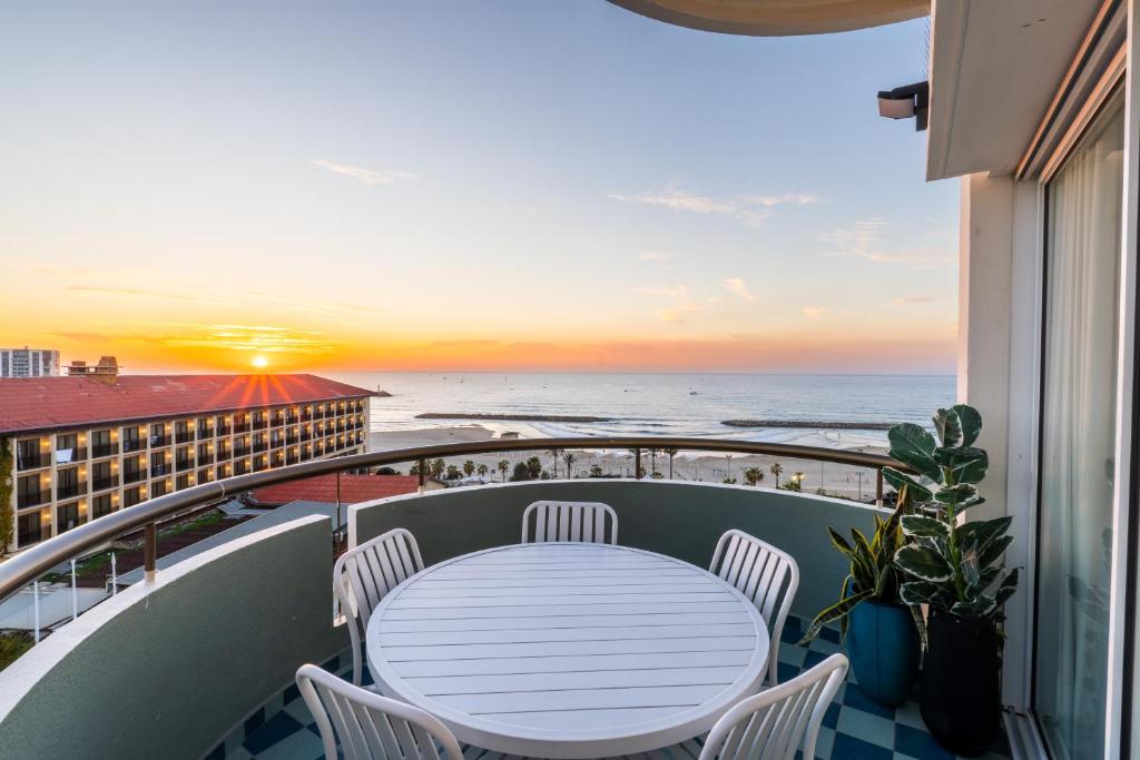 een tafel en stoelen op een balkon met uitzicht op de oceaan bij Sunsets Paradise 2BR with Private Parking in Herzelia 