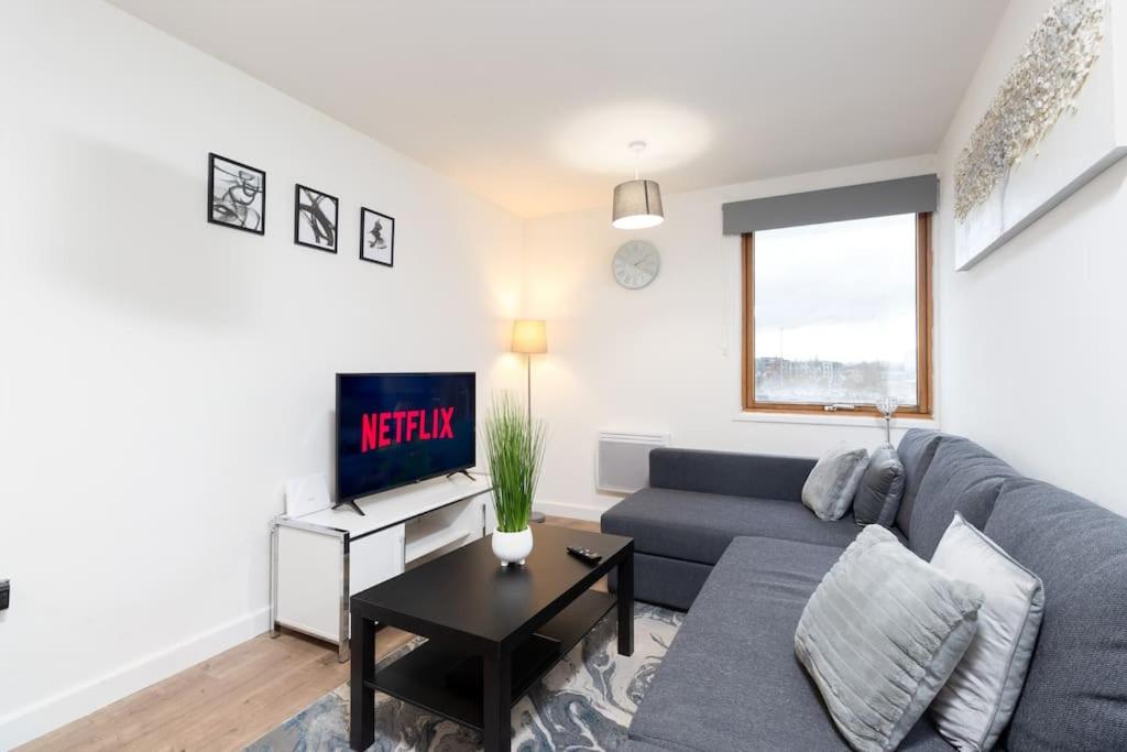 ein Wohnzimmer mit einem Sofa und einem TV in der Unterkunft Exquisite stays, modern apartment in city centre in Coventry