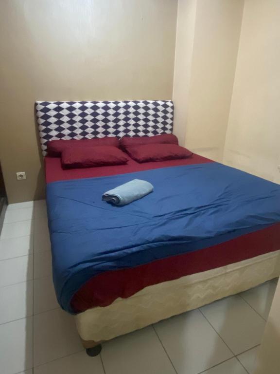 a bed with a blue blanket and red pillows at Alkhafy property in Jakarta