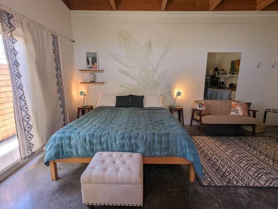 a bedroom with a bed and a couch and a chair at Eco-Farm Self-Contained Studio in Pahoa