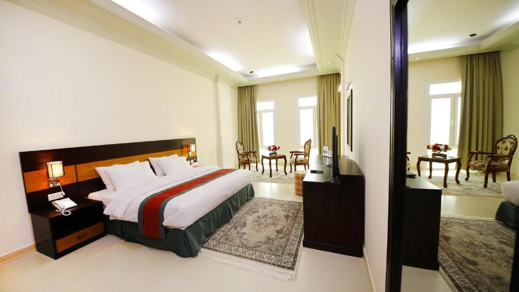 Habitación de hotel con cama y sala de estar. en Muscat International Hotel Plaza en Salalah