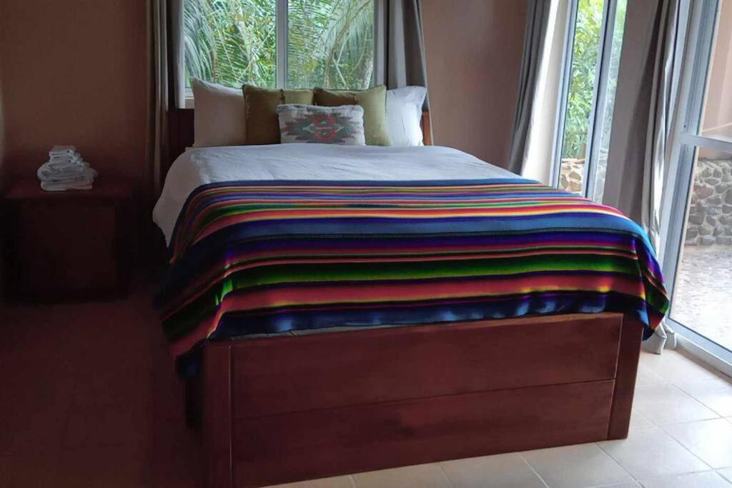 a bed with a colorful blanket on it next to a window at La Hacienda Belize Guest House in Benque Viejo del Carmen