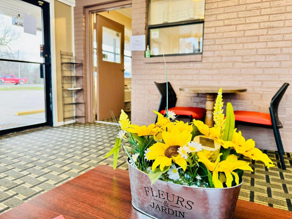 un cubo de flores amarillas sentado en una mesa en Holiday Pines Inn and Suites en Jay