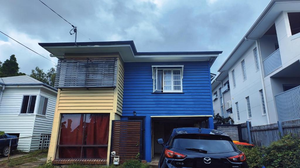 una casa blu con una macchina parcheggiata di fronte di Brisbane Budget Homestay a Brisbane