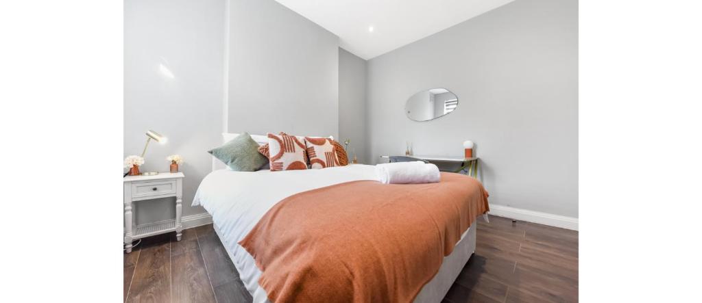 a white bedroom with a bed with an orange blanket at Cozy 3 Bedroom Flat in London! in London