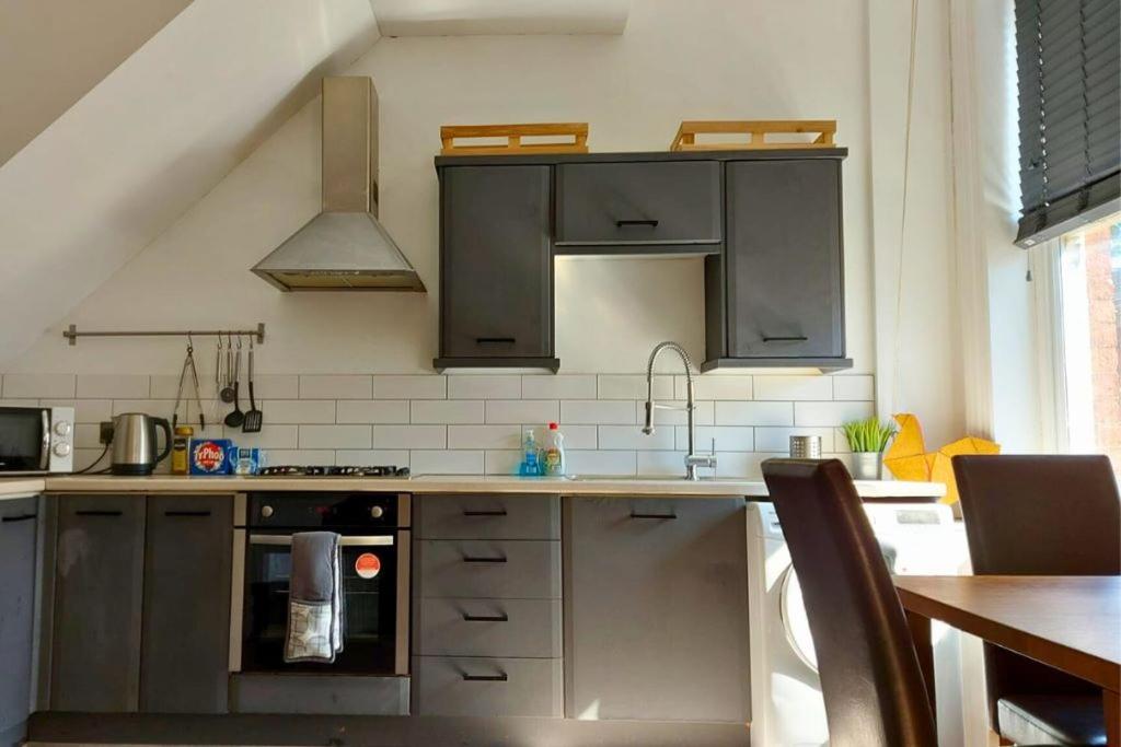 eine Küche mit Küchengeräten aus Edelstahl und einem Tisch in der Unterkunft Large Studio Room in City Centre (Shared Bathroom) in Preston