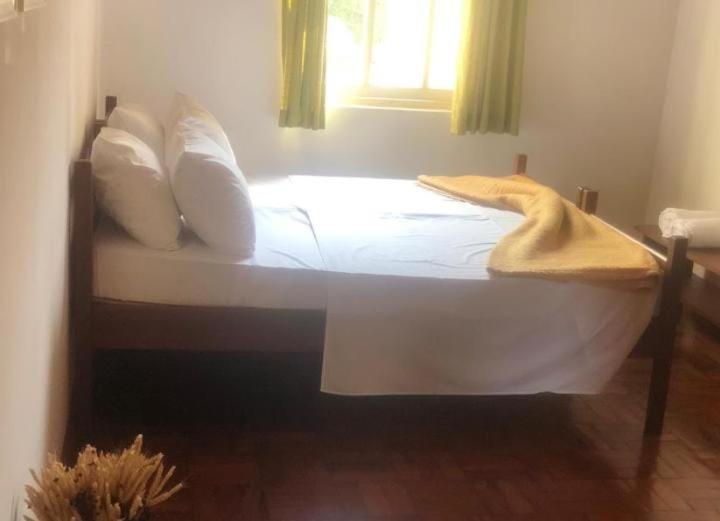 a white bed with a blanket on it in a room at Pousada Vila do Sítio in Mairiporã