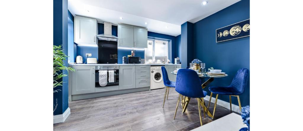 a kitchen with blue walls and a table and chairs at Sleek Modern 3BR Flat in Nunhead in London