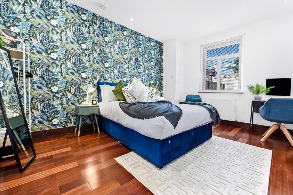 ein Schlafzimmer mit einem blauen Bett und einer blau-weißen Wand in der Unterkunft Enchanted Oasis: A Cozy Flat w/ Botanical Charm in Hanwell