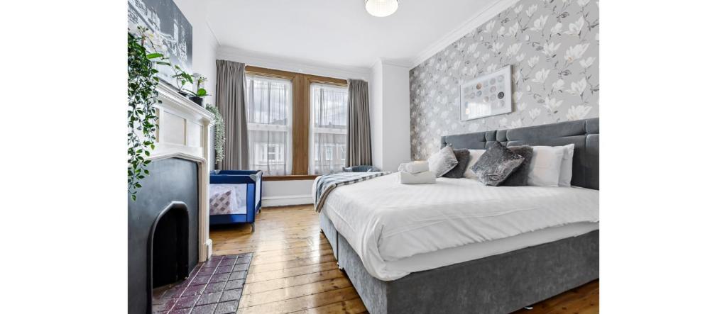 een slaapkamer met een groot bed en een open haard bij City Escape: Sleek and Comfy 3 BR House w/ Garden in Hither Green