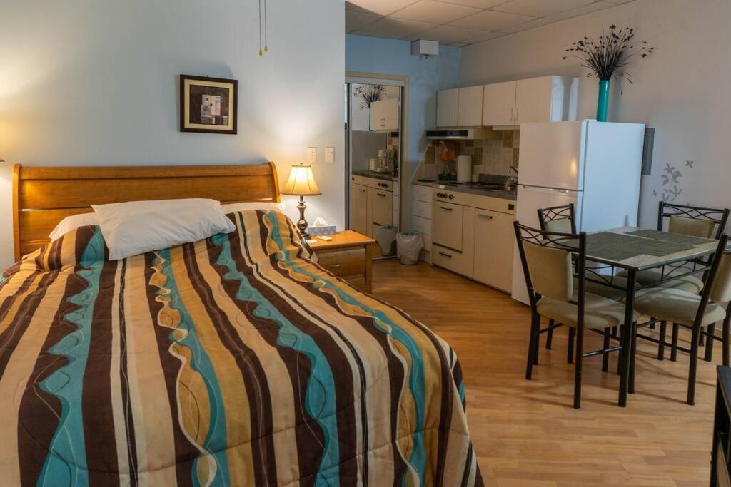 ein Schlafzimmer mit einem Bett und einem Tisch sowie eine Küche in der Unterkunft 227 Le confort de l'Auberge ! in Trois-Rivières