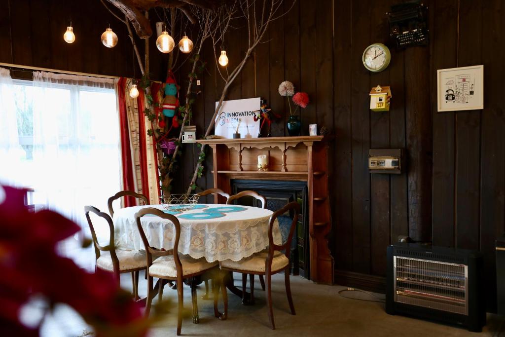 a dining room with a table and chairs and a clock at Miranda Farm close to airport！ in Kaiapoi