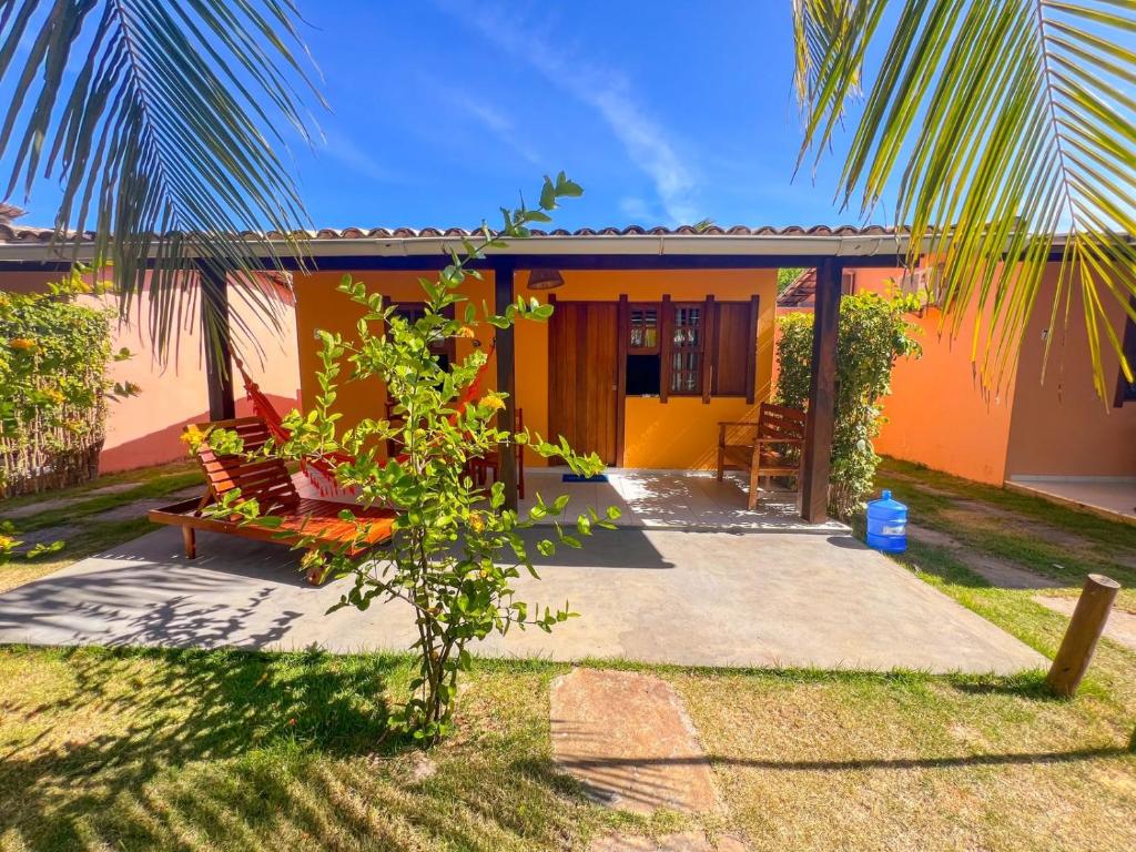 a yellow and orange house with a palm tree at Chalés Coco Verde - Praia de Itacimirim in Itacimirim