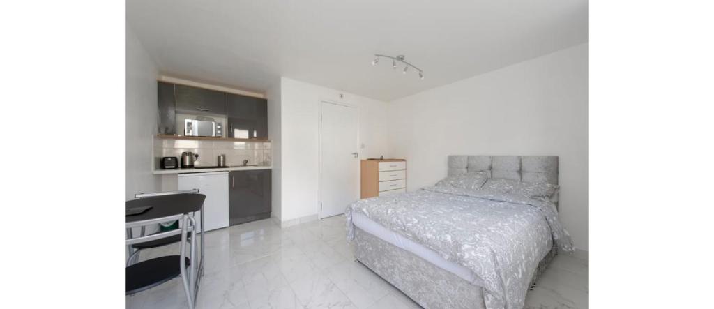 a white bedroom with a bed and a kitchen at Newly Renovated Cozy Studio in North London in London