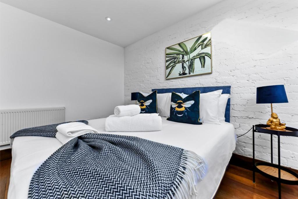 una camera da letto con un grande letto con cuscini blu e bianchi di Fresh and Cosy Two Bedroom Flat a Hanwell