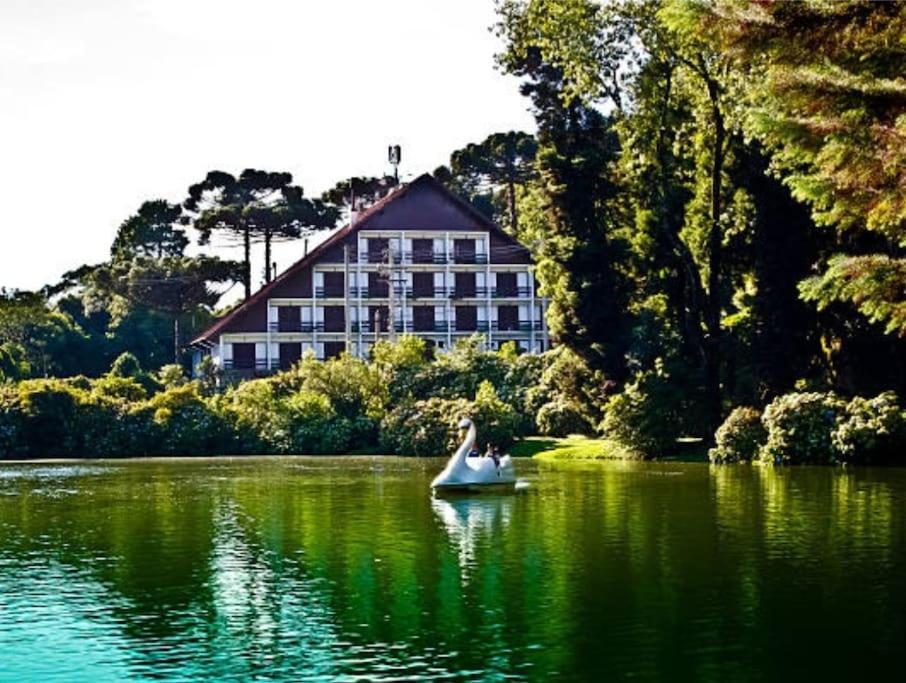 um barco em um lago em frente a um grande edifício em Casa Missões Dill Haus 1 em Gramado