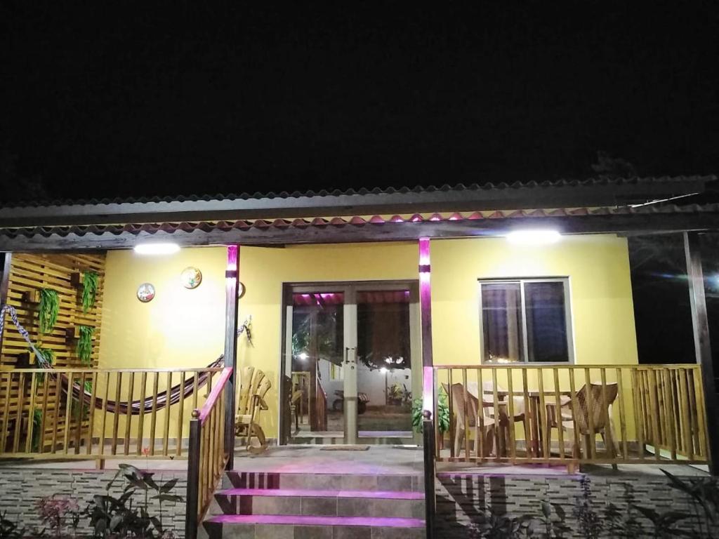 una casa amarilla con escaleras púrpuras delante por la noche en Baruch Tropical Ranch, en Los Santos