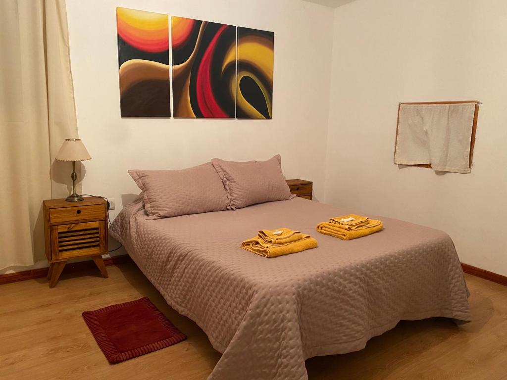 ein Schlafzimmer mit einem Bett und einem Gemälde an der Wand in der Unterkunft SAN MARINO in Villa María
